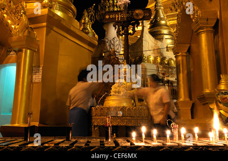 Fervent pèlerin pour verser de l'eau faisant offrande à la statue de Bouddha de la pagode Shwedagon post planétaire myanmar nuit nuit Banque D'Images