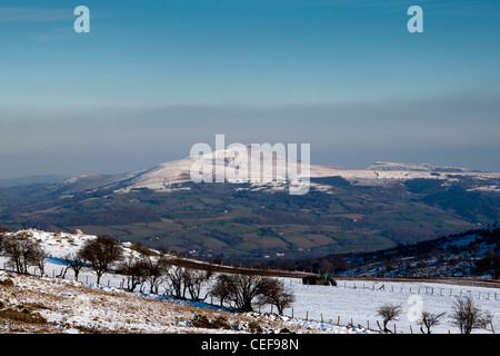 Un tracteur sur la neige avec une haute montagne enneigées,avec des champs verts au-dessous d'une ligne de neige clairement visible à l'arrière-plan au Royaume-Uni Banque D'Images