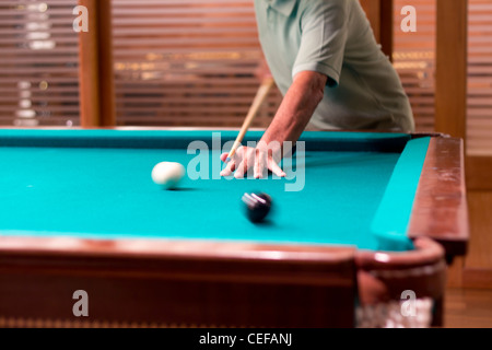 Un homme jouant de la dernière boule noire d'un jeu de billard. Motion d'effet sur les boules. Banque D'Images