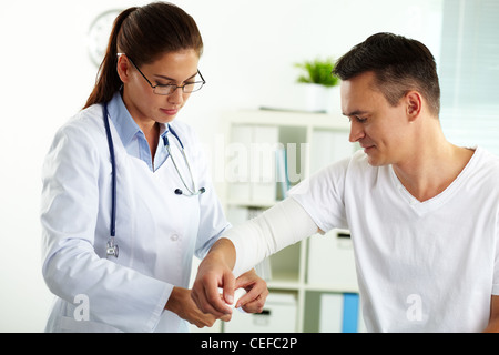 Portrait of female doctor de l'administration des premiers soins pour homme patient in hospital Banque D'Images