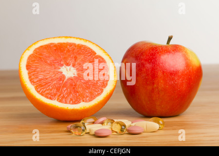 Complément alimentaire en face d'une pomme et une orange Banque D'Images