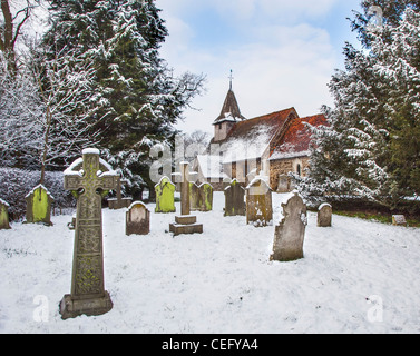 L'église St Nicolas, Church Hill, Pyrford, Surrey, Angleterre avec de graves et pierres tombales en croix cimetière, dans la neige Banque D'Images