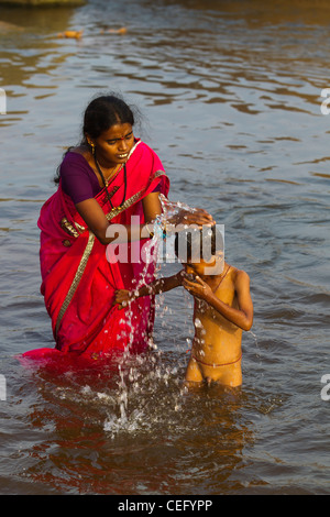 Mère indienne echelle de son fils sur les eaux de la rivière Tungabhadra, Hampi, Karnataka, Inde Banque D'Images