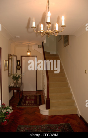 Plafonnier chandelier et tapis d'escalier crème neutre en salle avec parquet en bois sur tapis Banque D'Images