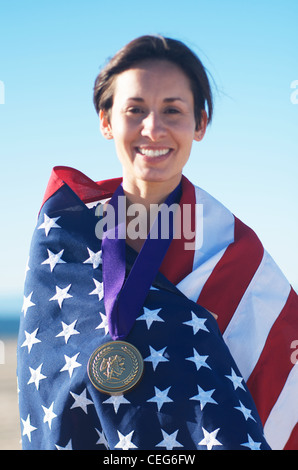 Portrait d'une femme enveloppée dans un drapeau américain portant une simulation d'une médaille d'or olympique. Banque D'Images