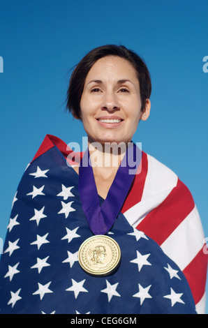 Portrait d'une femme enveloppée dans un drapeau américain portant une simulation d'une médaille d'or olympique. Banque D'Images