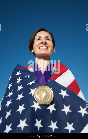 Portrait d'une femme enveloppée dans un drapeau américain portant une simulation d'une médaille d'or olympique. Banque D'Images