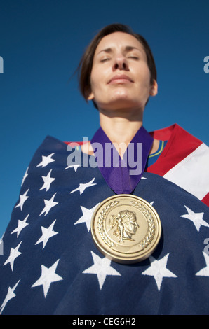 Portrait d'une femme enveloppée dans un drapeau américain portant une simulation d'une médaille d'or olympique. Banque D'Images