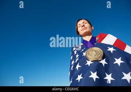 Portrait d'une femme enveloppée dans un drapeau américain portant une simulation d'une médaille d'or olympique. Banque D'Images