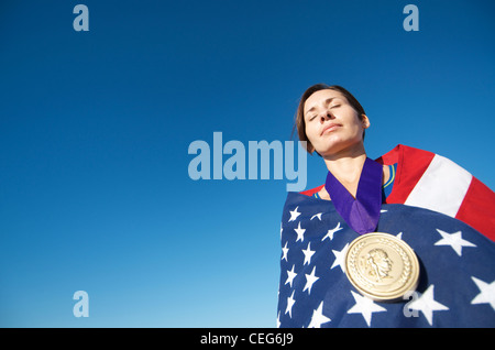 Portrait d'une femme enveloppée dans un drapeau américain portant une simulation d'une médaille d'or olympique. Banque D'Images