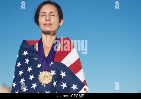 Portrait d'une femme enveloppée dans un drapeau américain portant une simulation d'une médaille d'or olympique. Banque D'Images