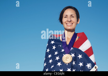 Portrait d'une femme enveloppée dans un drapeau américain portant une simulation d'une médaille d'or olympique. Banque D'Images