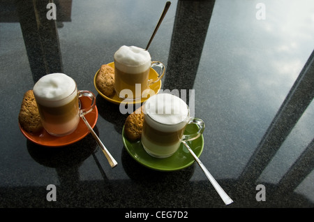 Cuisine de granit noir commode avec trois tasses en verre 'café au lait', soucoupes colorées et de réflexion à partir de la fenêtre . Banque D'Images