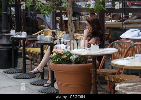 Une jeune femme dans un café, de parler dans un téléphone cellulaire, New York City Banque D'Images