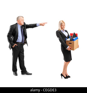 Portrait d'un patron en colère tirant une femme en costume portant un fort d'objets personnels isolé sur fond blanc Banque D'Images