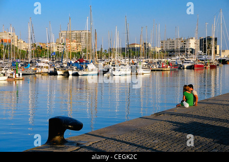 Un couple jouit du coucher du soleil à la marina de Port Vell, Barcelone, Espagne. Banque D'Images