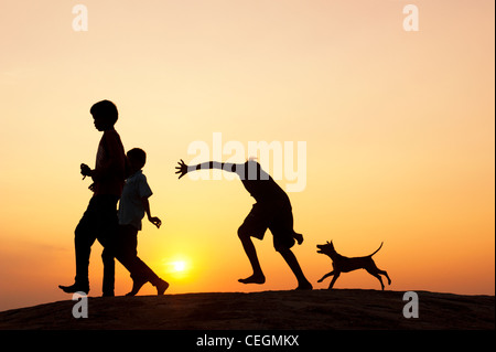 Silhouette de jeune Indien enfants courant et jouant avec un chiot. L'Inde Banque D'Images