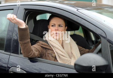 Une femme dans ses années 20s en colère conduisant une voiture avec la route Rage criant sur d'autres automobilistes au Royaume-Uni (posé par le modèle) Banque D'Images