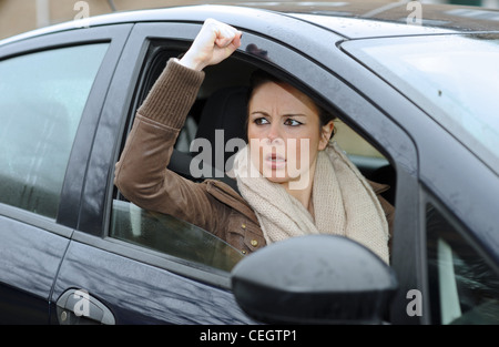 Une femme dans ses années 20s en colère conduisant une voiture avec la route Rage criant sur d'autres automobilistes au Royaume-Uni (posé par le modèle) Banque D'Images