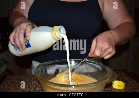 Woman pouring lait en mélange omelette Banque D'Images