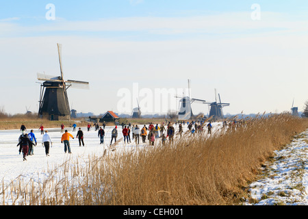 Scène typiquement néerlandais montrant les gens patinage sur glace naturelle avec les moulins à vent de Kinderdijk en toile de fond. Banque D'Images