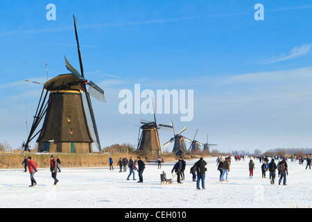 Scène typiquement néerlandais montrant les gens patinage sur glace naturelle avec les moulins à vent de Kinderdijk en toile de fond. Banque D'Images