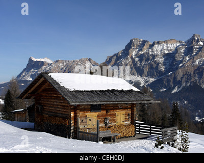 Chalet en bois dans la neige près de San Cassiano, dans les Dolomites en Italie. Montagnes derrière typique de salon, appelé le Contarines. Banque D'Images