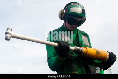 Aviation Boatswain's Mate (Equipment) Airman Martin Marenette inspecte une barre de retenue sur le pont de vol du porte-avions de classe Nimitz USS John C. Stennis. John C. Stennis est en déploiement pendant sept mois dans le domaine de responsabilité de la 7e flotte américaine. Banque D'Images