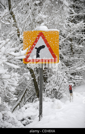 Un panneau de circulation par temps neigeux avertissement d'un virage de la route UK Banque D'Images