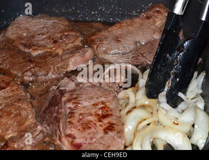 Steak et les oignons dans une poêle de cuisson Banque D'Images