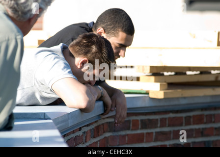 (De gauche à droite) George Courtsunis et Howard Kellogg se repaire sur le bord du toit de Baker House avant de déposer le piano. Banque D'Images