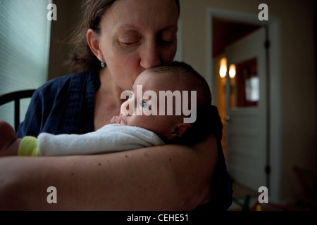 Mère embrassant sa fille nouveau-né à la maison. Banque D'Images