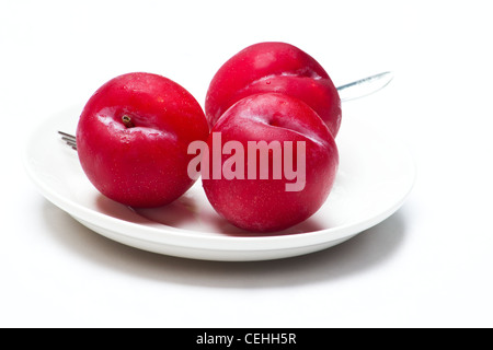 Trois prunes rouges sur fond blanc Banque D'Images