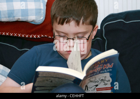 Boy reading Diary of a wimpy kid par Jeff Kinney sur hos dixième anniversaire Banque D'Images
