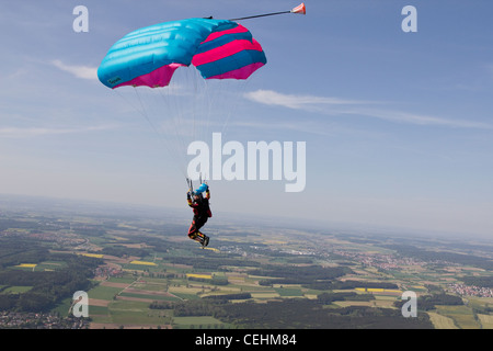 Parachutiste sous voile est survolant des champs verts dans le ciel bleu et s'apprête à enregistrer des terres sur le terrain Banque D'Images