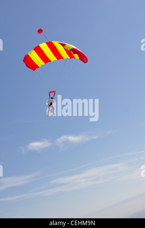 Parachutiste sous voile vole dans le ciel bleu avec quelques petits nuages et il se prépare à enregistrer des terres sur le terrain. Banque D'Images