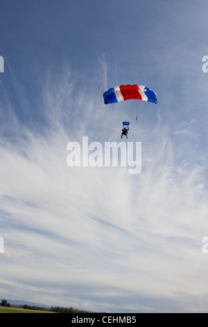 Couple parachutiste sous voile sont survolant des champs verts dans le ciel bleu et se préparent à enregistrer des terres sur le terrain. Banque D'Images