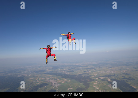 Les parachutistes sont flying head jusqu'au sein d'une équipe et d'essayer le sit fly de poste sur une herbe paysage paysage spectaculaire. Banque D'Images