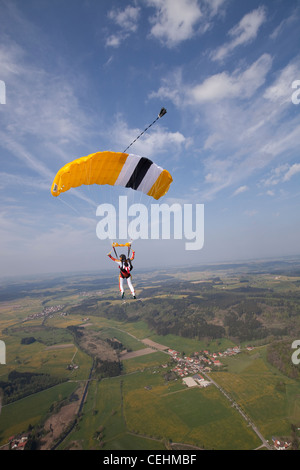 Parachutiste sous voile est survolant des champs verts sur le ciel bleu et s'apprête à enregistrer des terres sur le terrain. Banque D'Images