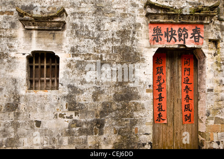 Une vieille maison avec un style traditionnel unique fenêtre et porte. Les couplets sur la porte rouge célébrant le nouvel an chinois. Banque D'Images