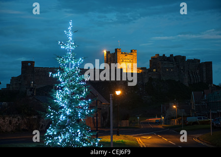 Château de Bamburgh, Northumberland, Angleterre, Royaume-Uni, de l'Ouest, au crépuscule, avec un arbre de Noël dans l'avant-plan Banque D'Images