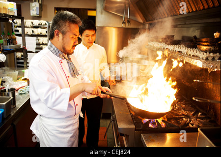 Chef de remuer la friture avec un wok, dans un restaurant coréen. Banque D'Images