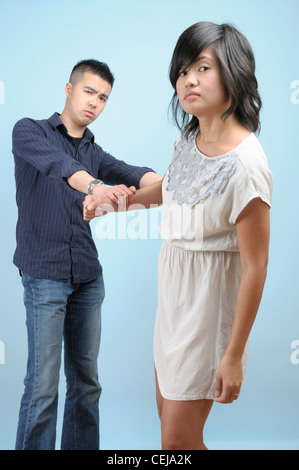 Un jeune homme tente d'empêcher une jeune femme asiatique qui est en colère à propos de quelque chose Banque D'Images