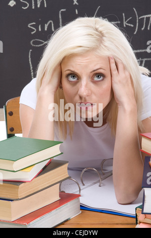 A souligné le lycée ou l'université female student sitting au cours de mathématiques. Tableau noir avec des formules mathématiques complexes Banque D'Images