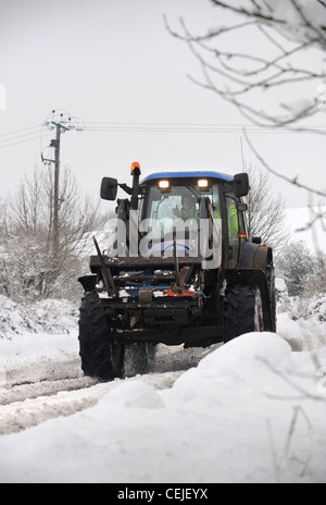 Les agriculteurs d'un tracteur dans la neige Gloucestershire UK Banque D'Images