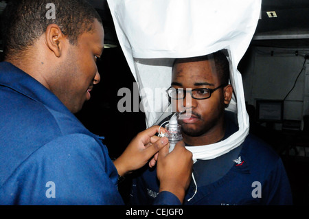 Technicien de formation 2e classe Raymond Jackson effectue un test d'ajustement respiratoire sur le technicien de Hull 3e classe Adrine Thomas à bord du navire d'atterrissage amphibie déployé à l'avant USS Germantown (LSD 42). Germantown, avec des éléments embarqués de la 31e unité expéditionnaire maritime (MEU), est actuellement en cours pour soutenir l'exercice Cobra Gold 2012, un exercice annuel conjoint et multinational parrainé par la Thaïlande et les États-Unis, conçu pour faire progresser la sécurité dans toute la région Asie-Pacifique et améliorer l'interopérabilité avec les pays participants. Banque D'Images