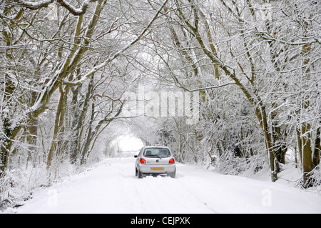 Neige scène Ford Fiesta car driving on country road lane ci-dessous de tunnel d'arbres couverts de neige en hiver wonderland Brentwood Essex England UK Banque D'Images