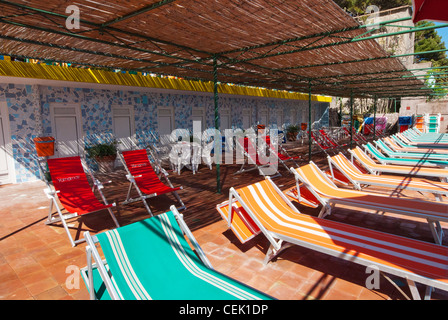 Transats dans une ligne sur terrasse avec cabines de plage derrière, Capri, italie Banque D'Images