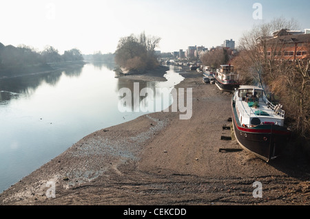 L'hiver à marée basse sur la Tamise à Londres, avec des bateaux-maison sur la banque de Brentford. Vu de Kew Bridge à l'ouest. Banque D'Images