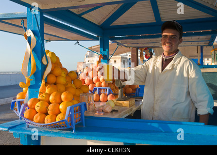 Man le jus d'orange fraîchement pressé, Essaouira, Maroc Banque D'Images
